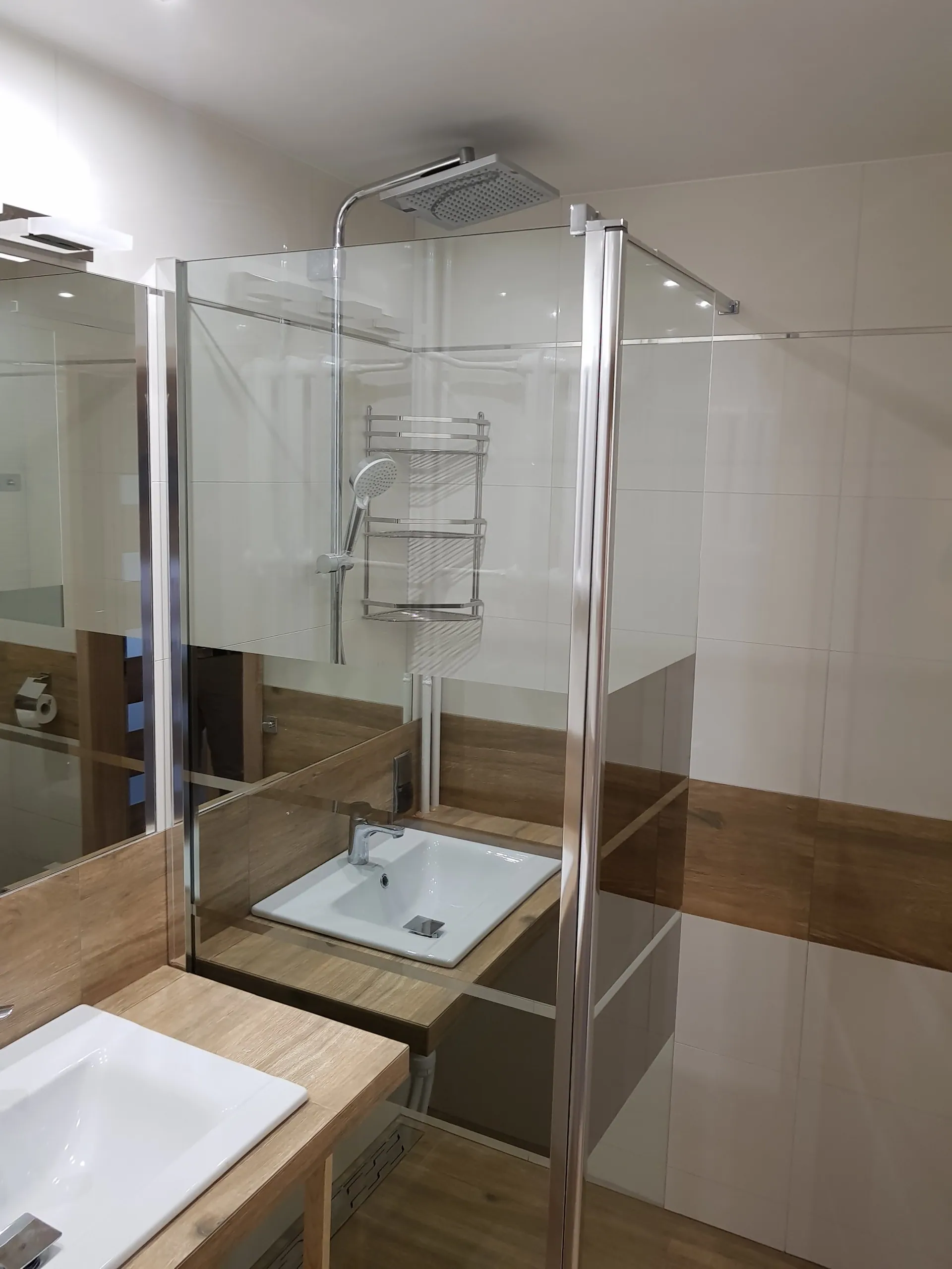 Łazienka z kabiną walk-in z deszczownicą i drewnianym blatem z dwiema umywalkami.